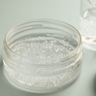 a clear gel that has been created using xanthan gum clear is in a clear cosmetic jar and sits on a plain surface