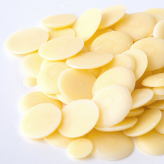 Image of cocoa butter buttons or pellets on a white surface. This is an image of where to buy cocoa butter in australia for skincare and soap