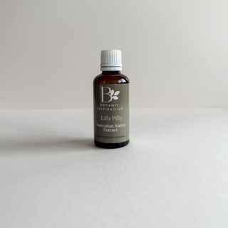 Amber glass bottle sits on a white surface with a white background. The bottle has a white cap and green label which reads Lilly Pilly Australian Native Extract. The brand is Botanic Inspiration
