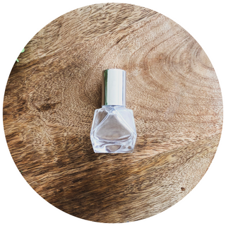 A small glass roller bottle with a diamond shape sits on a wooden surface