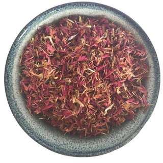 A round ceramic bowl holds vibrant purple dried cornflower petals