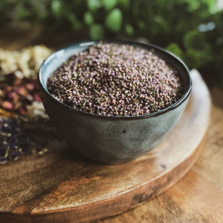 A bowl of heather flowers sits on a timber board